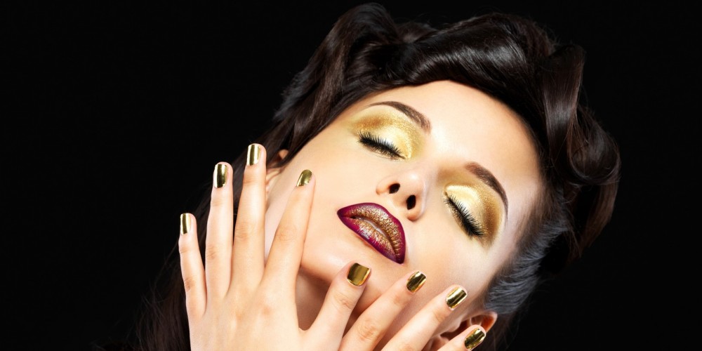 Beautiful brunet woman with golden nails and style makeup of eyes -  on black background